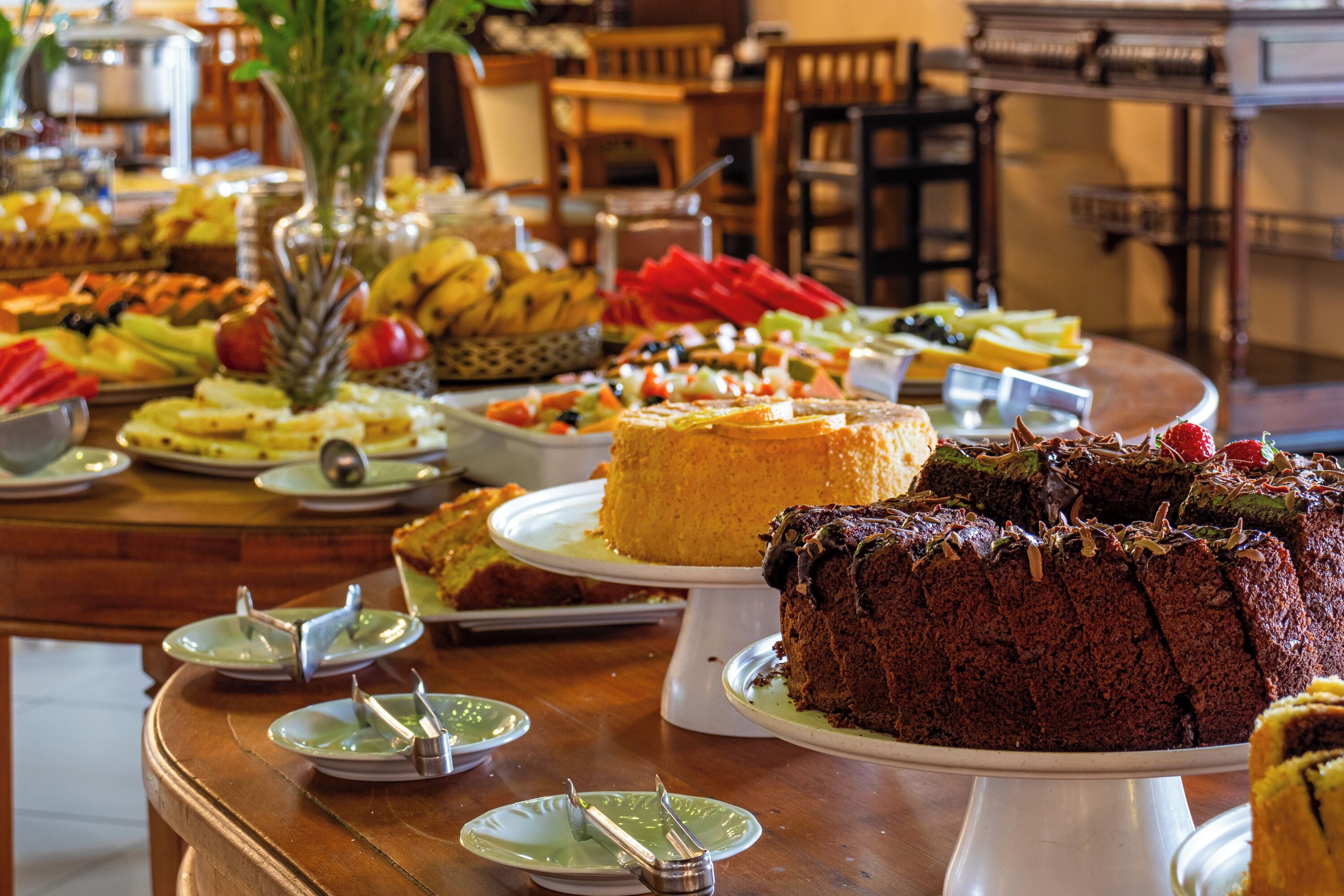 A buffet with various food items and a cake on a wooden table.