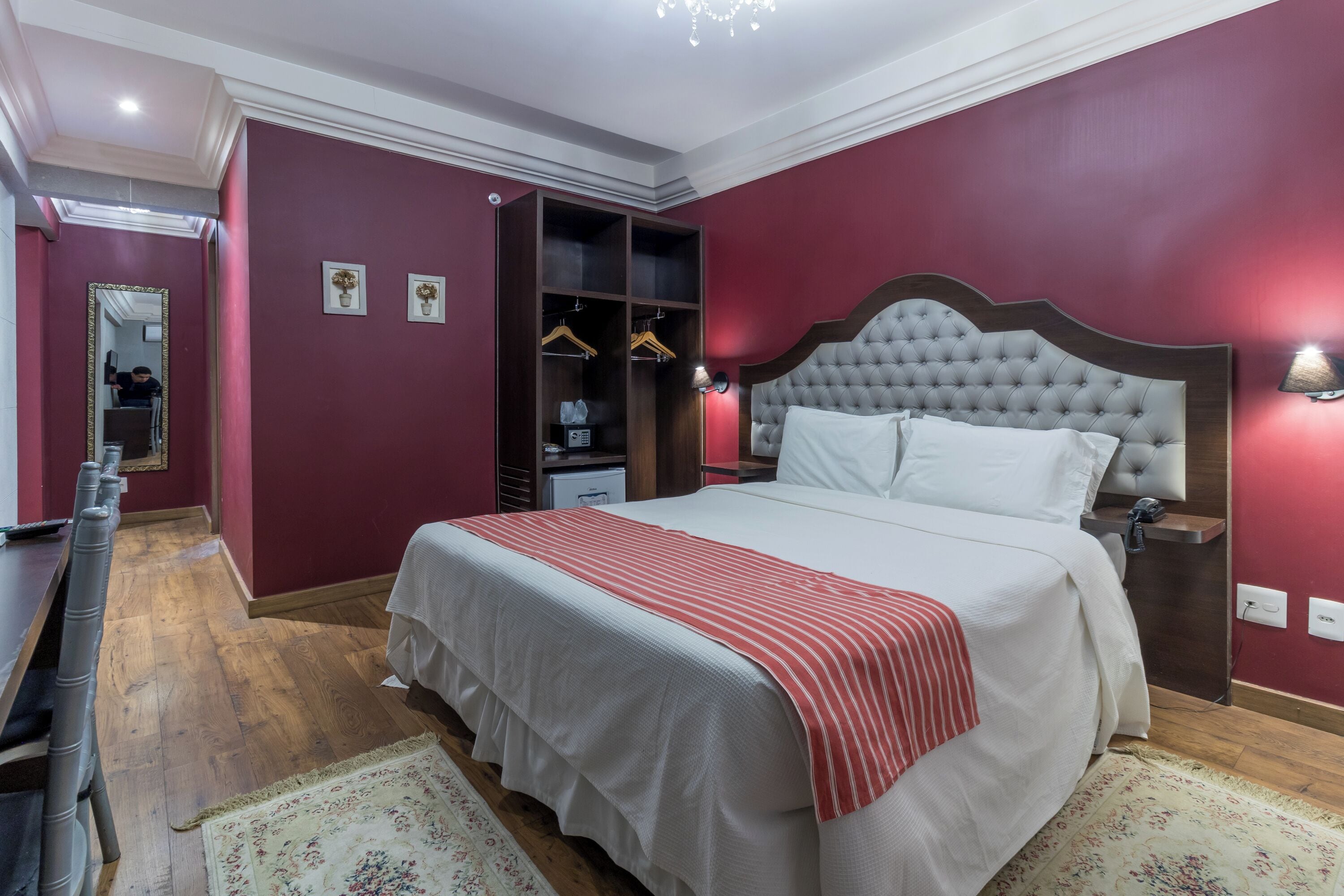 Quarto bem arrumado com uma cama grande, guarda-roupa e espelho.
