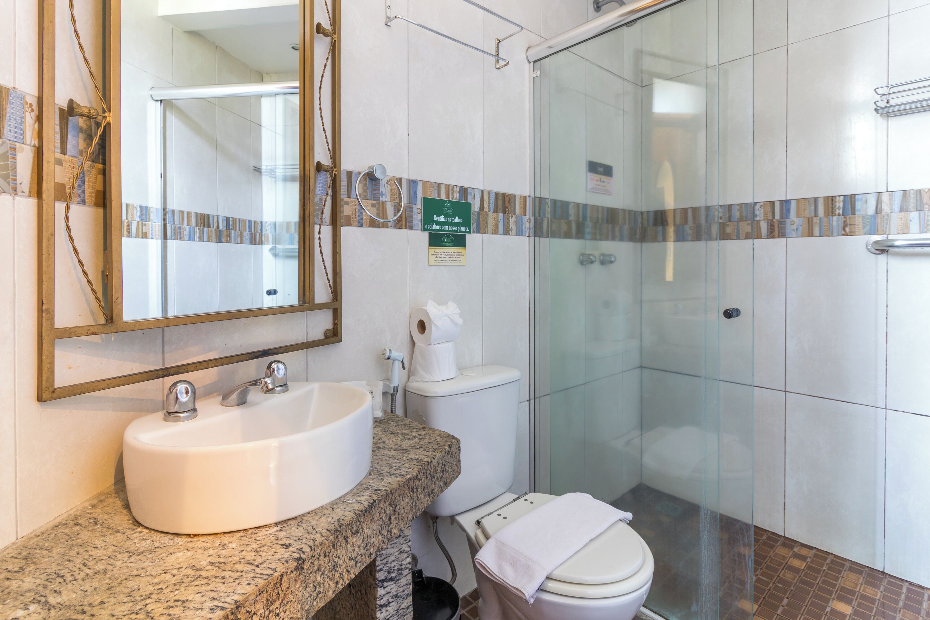 A bathroom with a granite countertop sink, a toilet, and a glass-enclosed shower.