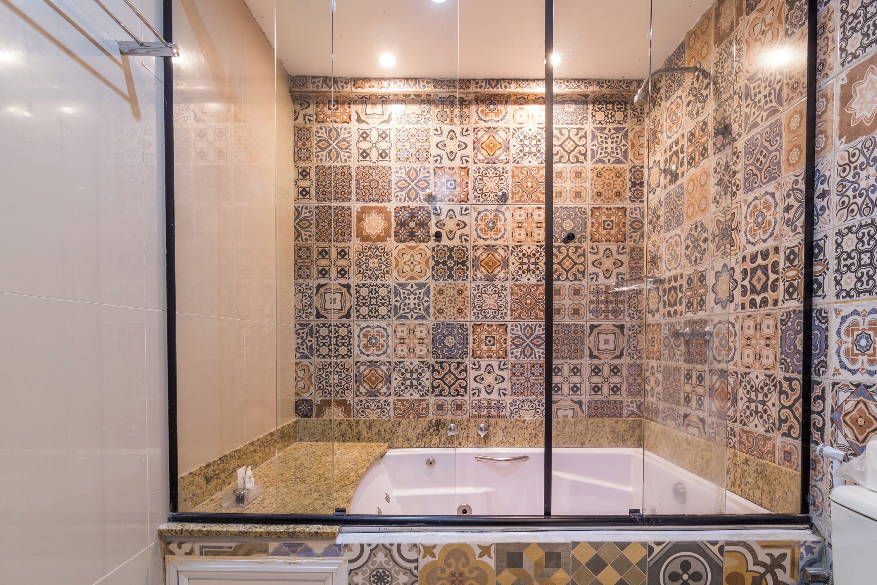 A bathroom with a large bathtub, tiled walls, and a glass shower enclosure.