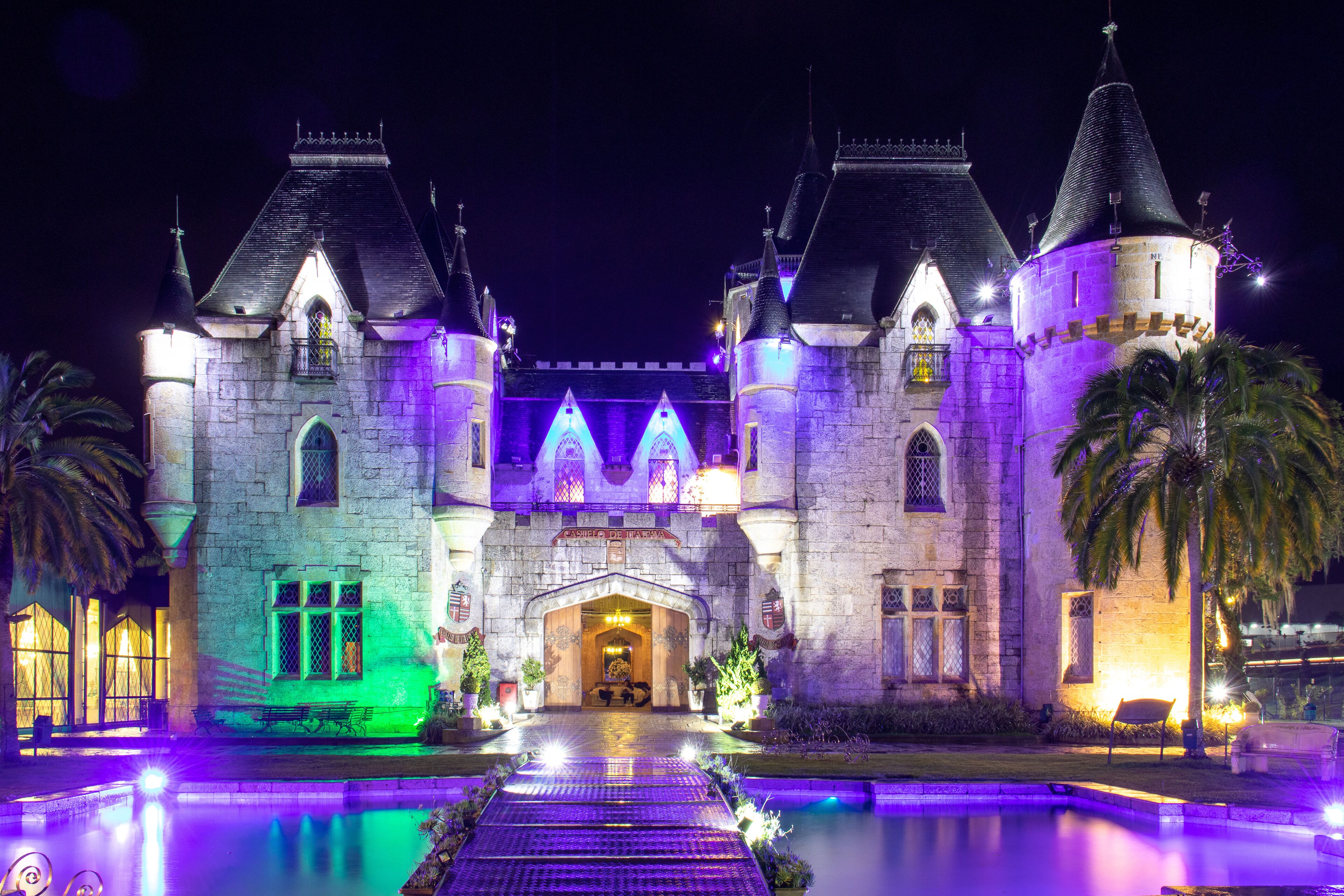 Un edificio al estilo de castillo con una entrada central, dos torres y un foso que lo rodea.