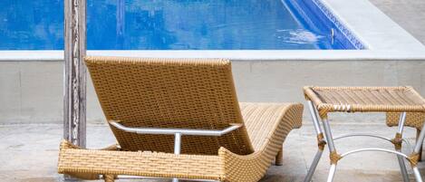 A pool area with a pergola, lounge chairs, and a dining table with chairs.