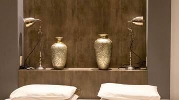 Une chambre d’hôtel avec deux grands vases posés sur une étagère, deux lampes de chevet et deux oreillers blancs sur le lit.