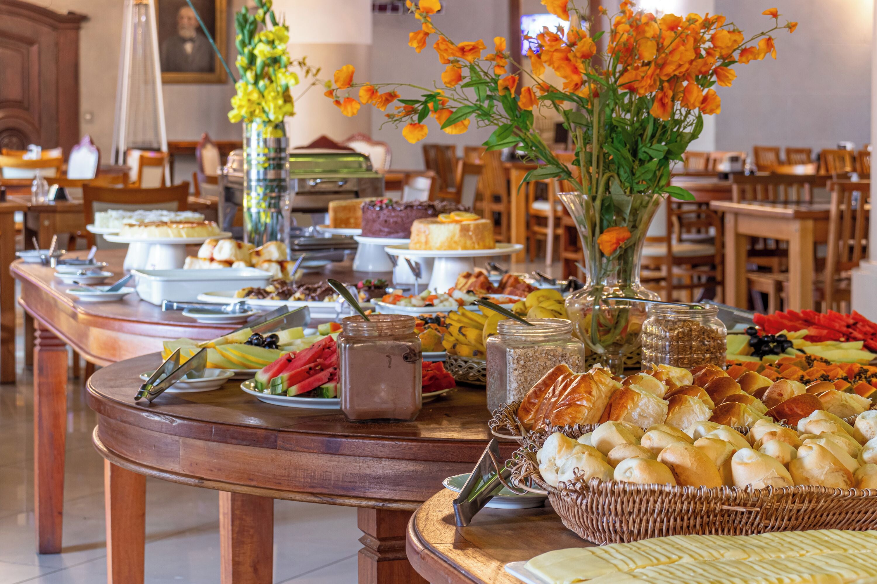 A buffet table with various food items and a vase of orange flowers.
