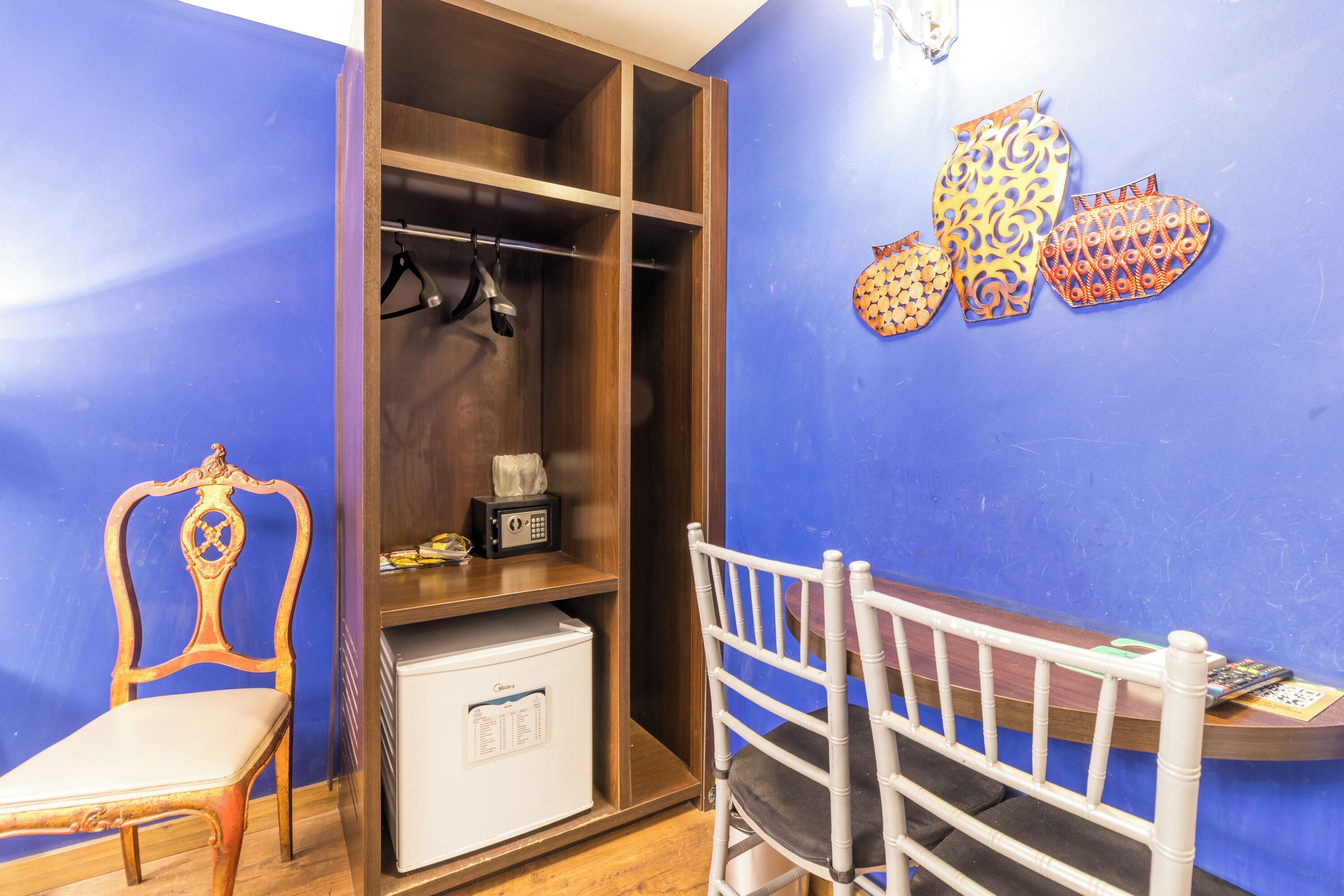 A room with a wooden wardrobe, a white chair, and a desk with a computer.