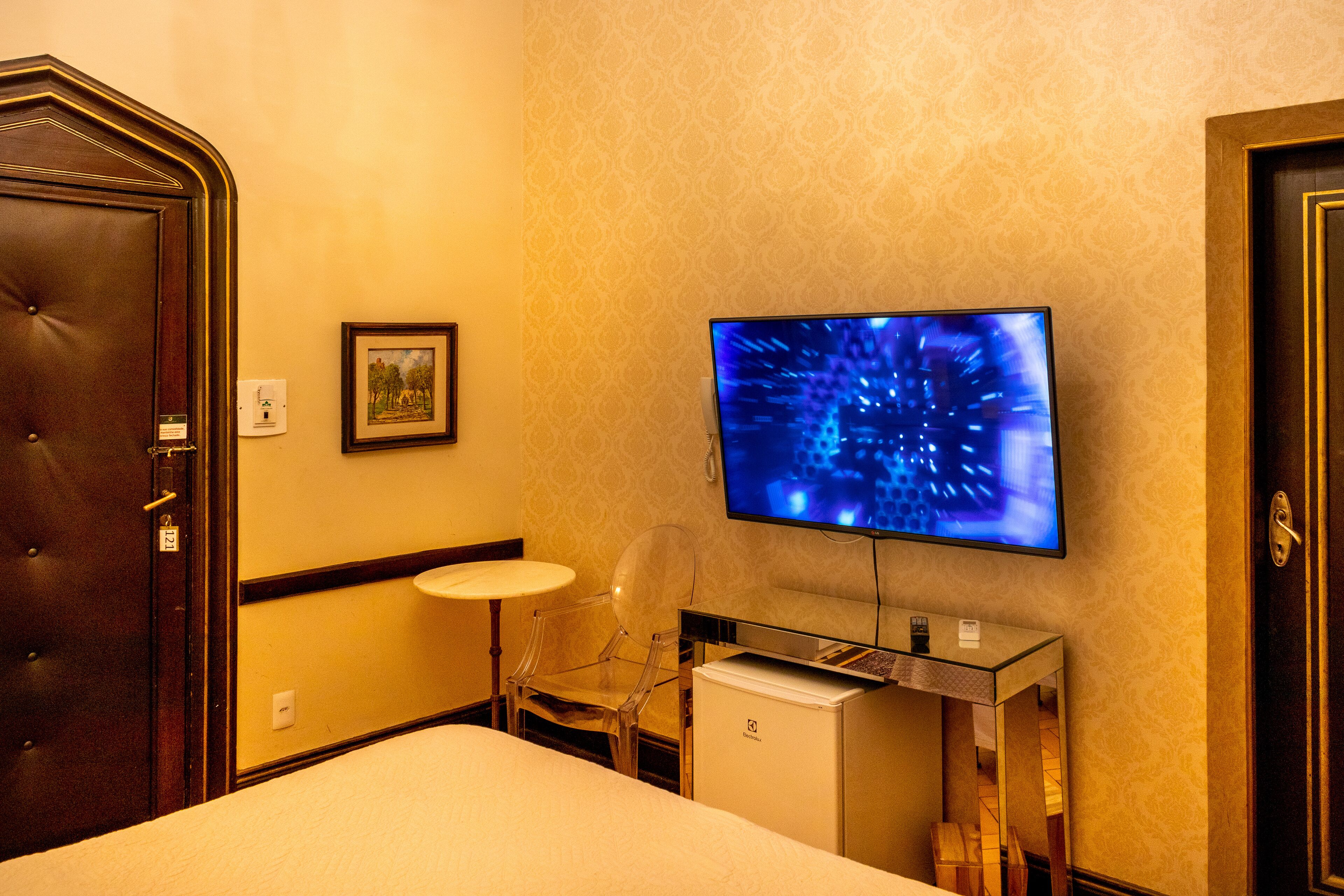 A hotel room with a bed, a desk with a computer, a television, and a chair.