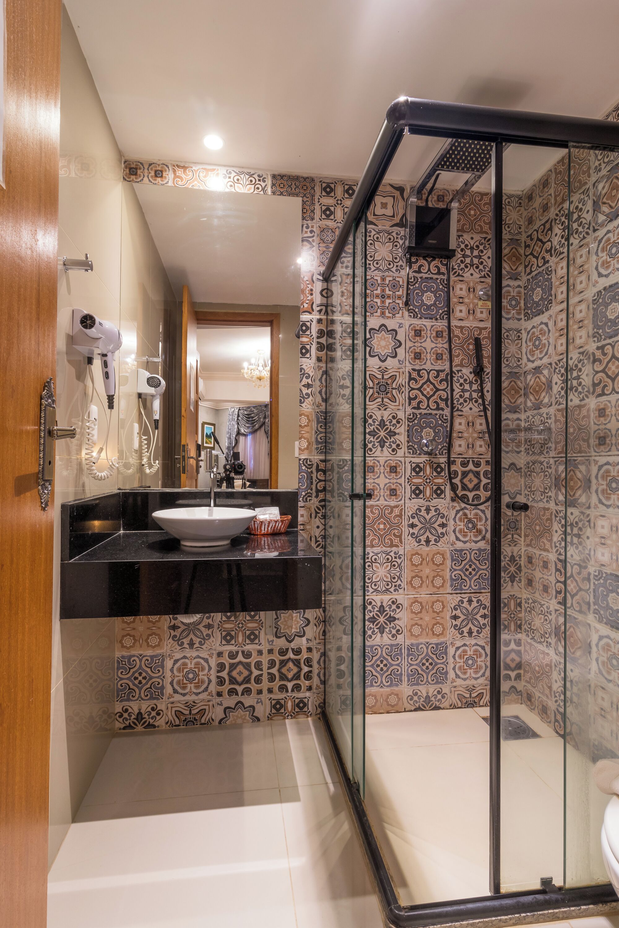 A bathroom with a black countertop, a white sink, and a glass shower enclosure.