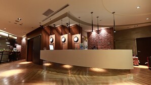 Un área de recepción moderna con un mostrador de madera, iluminación colgante y una pared de ladrillo.