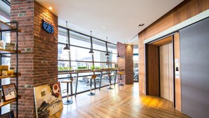 Un interior moderno con pared de ladrillo, piso de madera y una zona de bar con taburetes.