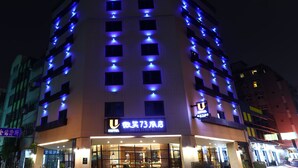 Un hotel de varios pisos iluminado con luces azules, y un cartel que indica que es el Hotel Smile 73.