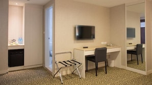 Hotellihuone, jossa on työpöytä, tuoli, televisio ja peili.