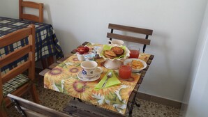 A dining table with a floral tablecloth, a coffee cup, a glass of juice, a bowl of cereal, and a plate of toast. - Luna Piena B&B (Lecce)