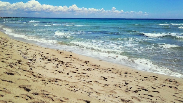 A sandy beach with footprints leading to the water, a clear sky, and calm waves. - Luna Piena B&B (Lecce)