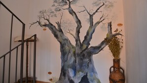 A staircase with a wall mural of a tree and a vase with dried plants. - Agriturismo Monaci Templari (Seborga)