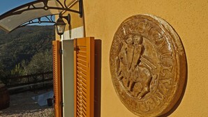 A wooden gate with a metal lamp post and a bronze plaque with inscriptions. - Agriturismo Monaci Templari (Seborga)