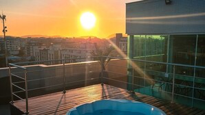 A rooftop with a hot tub, a glass wall, and a sunset view. - Paradiso Corporate - Cabo Frio (Cabo Frio)
