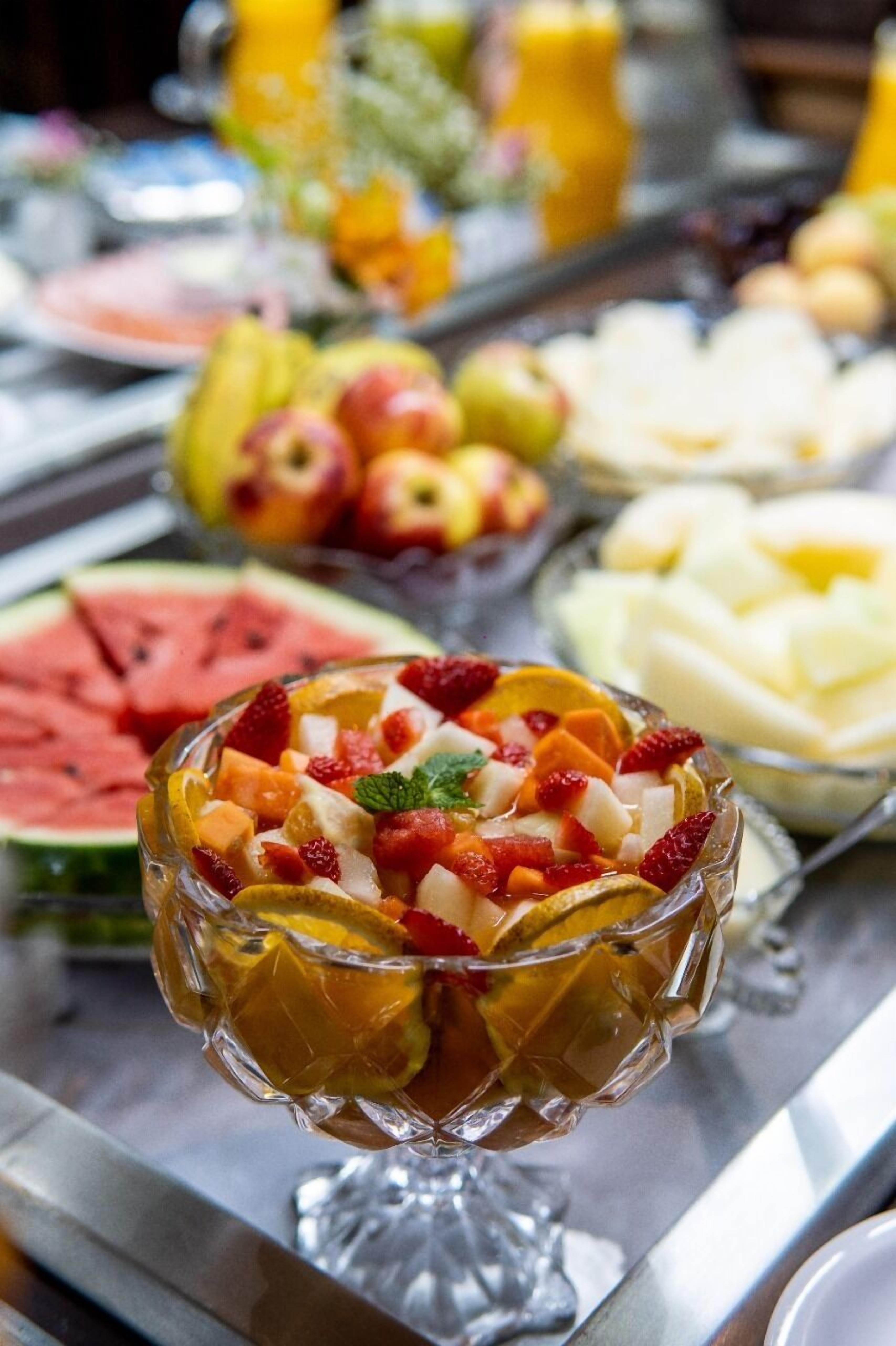 Un bufé con diversas frutas y un bol de ensalada de frutas.