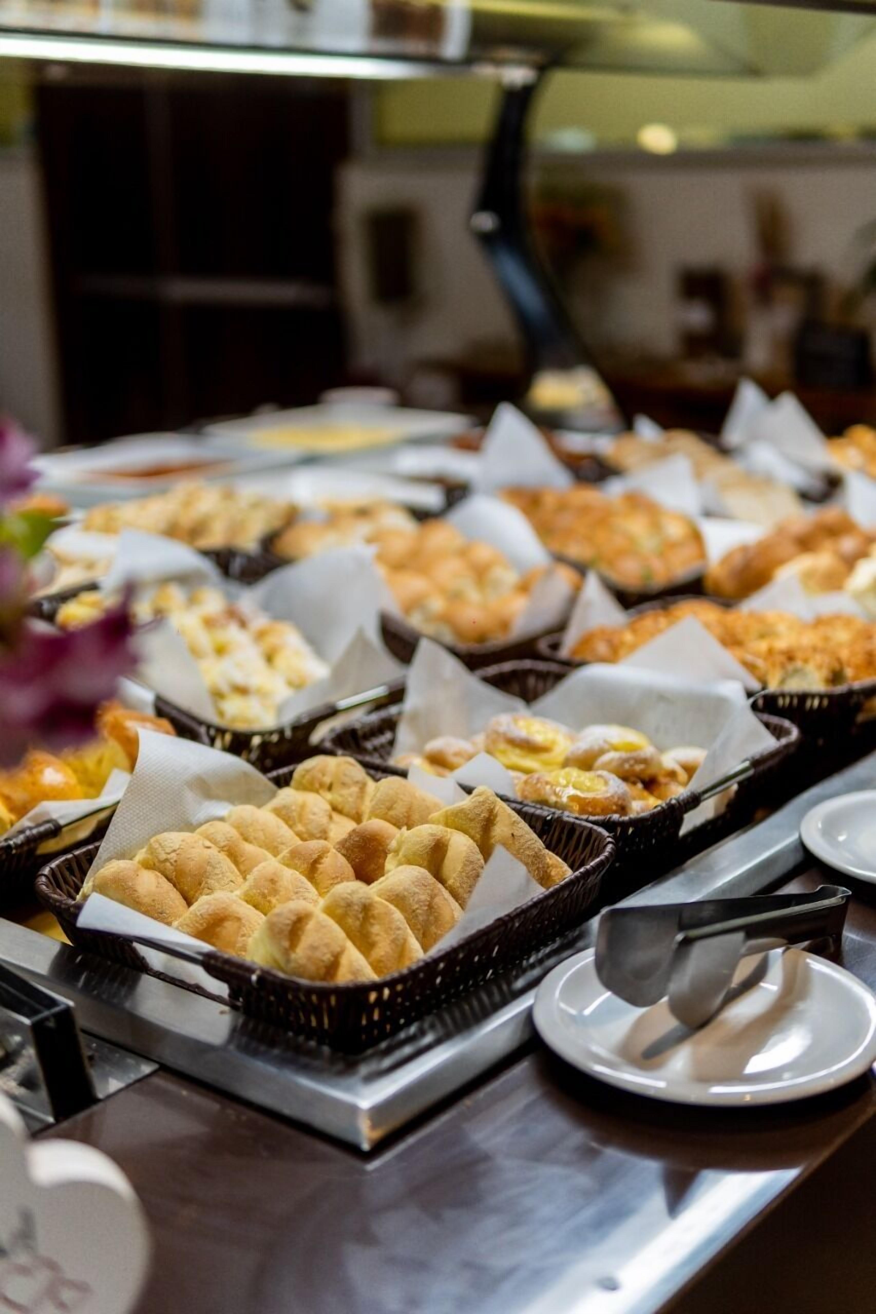 A buffet with various baked goods, including bread rolls and pastries, arranged on trays.