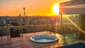 A rooftop pool with a hot tub, surrounded by a cityscape during sunset. - Paradiso Corporate - Cabo Frio (Cabo Frio)