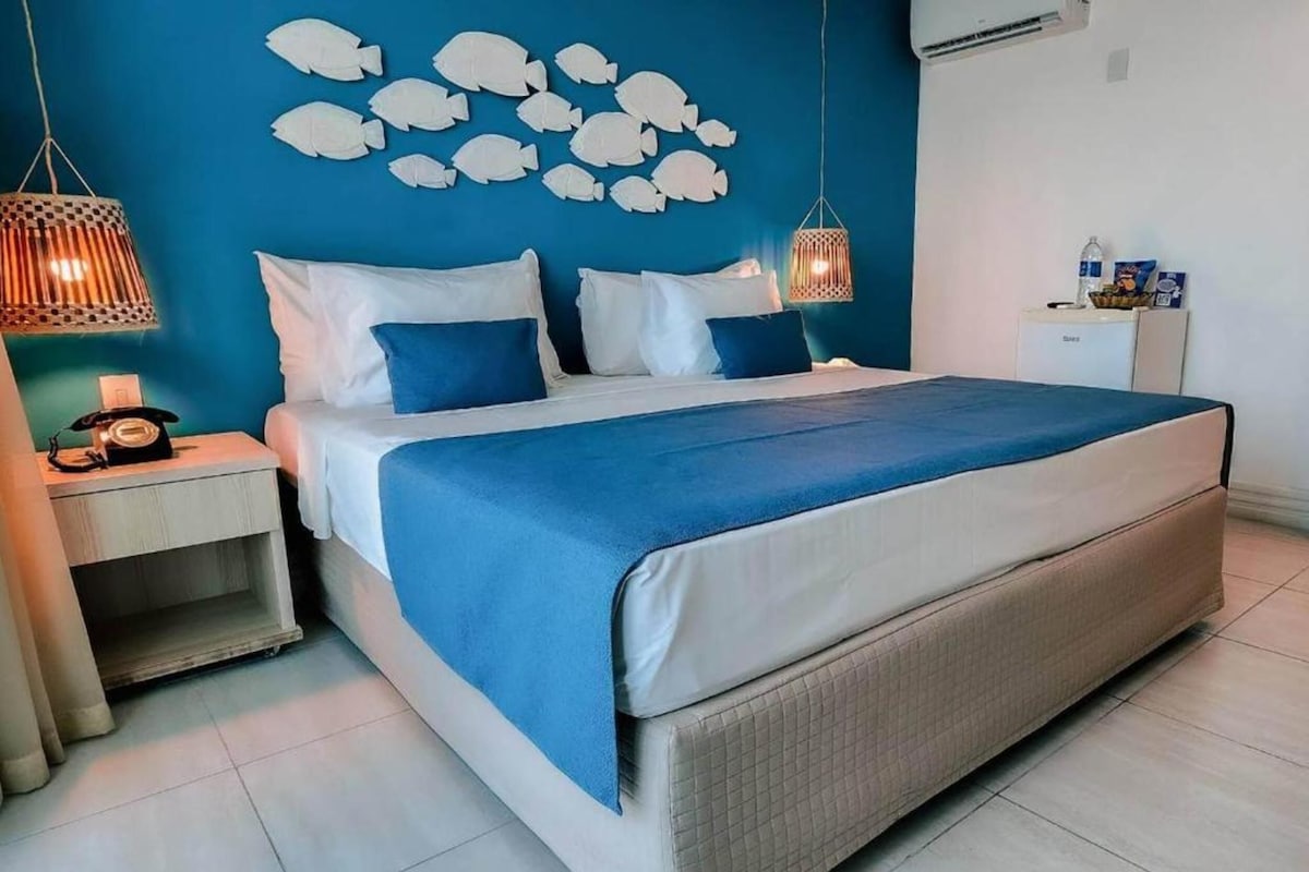 A bedroom with a bed, nightstands, a wall-mounted air conditioner, and a wall decoration.