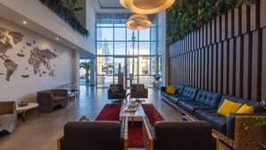 A spacious lobby with a large seating area, a world map on the wall, and a view of the outdoors. - Paradiso Corporate - Cabo Frio (Cabo Frio)