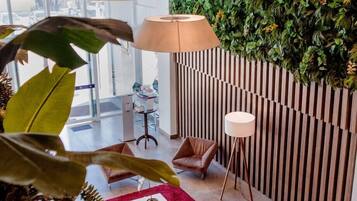 A modern lounge area with a green wall, comfortable seating, and a red rug.