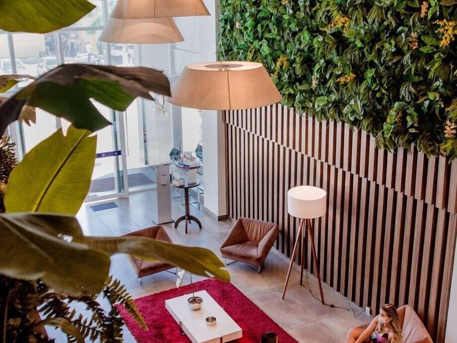 A modern lounge area with a green wall, comfortable seating, and a red rug.