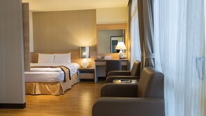 Et hotelværelse med seng, skrivebord, stol og lampe.