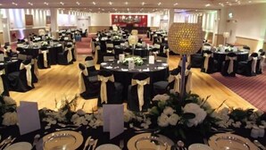 A banquet hall with round tables, black tablecloths, and white floral centerpieces. - Ashbourne House Hotel (Ashbourne)