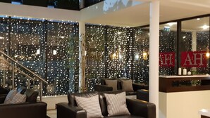 A modern interior with a seating area featuring leather sofas and a glass wall with decorative lights. - Ashbourne House Hotel (Ashbourne)