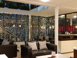Un interior moderno con una zona de estar que incluye sofás de cuero y un muro de vidrio con luces decorativas.