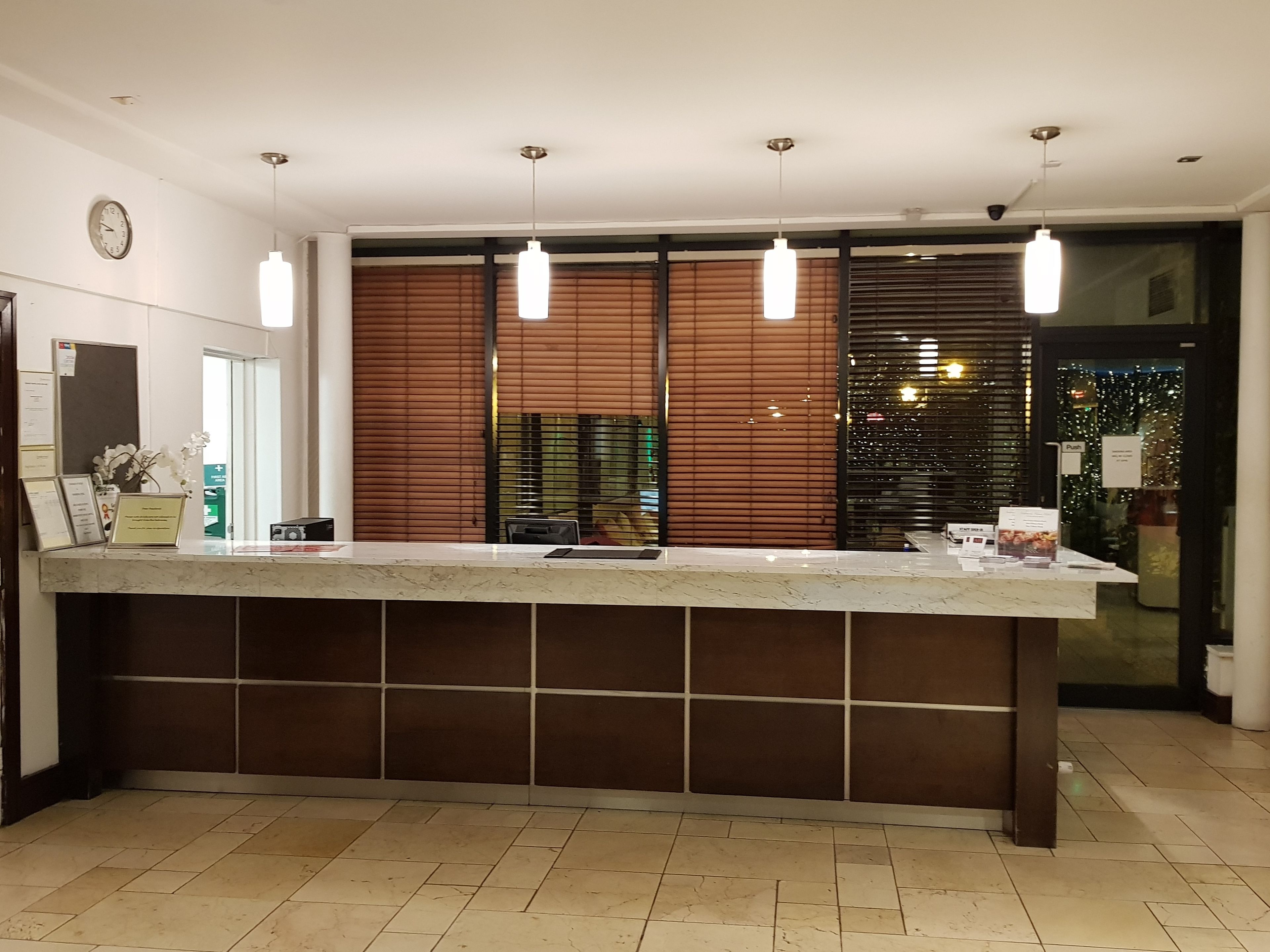 A reception area with a marble counter, wooden paneling, and pendant lighting.