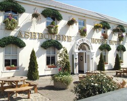 Hotel Ashbourne House con fachada tradicional, terraza al aire libre y cestos de flores colgantes.