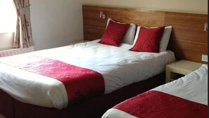 A double bed with red and white bedding, a wooden headboard, and a small bedside table. - Ashbourne House Hotel (Ashbourne)