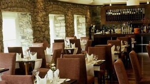 A restaurant with stone walls, wooden tables, and chairs. - Ashbourne House Hotel (Ashbourne)