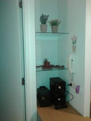 Cozy retreat with a glass shelf unit, potted plants, and a comfortable seating area.