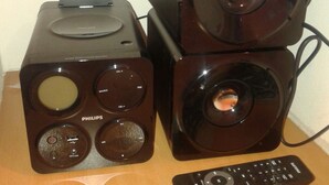 Un sistema estéreo Philips con control remoto sobre una superficie de madera.