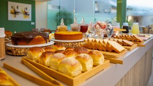 Un bufé con diversas opciones de panadería, incluyendo pan, bollos y un pastel.