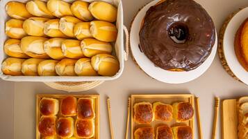 Una bandeja de panecillos, un donut cubierto de chocolate y un plato de pan.