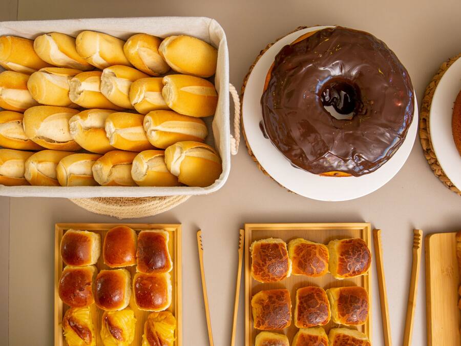 Una bandeja de panecillos, un donut cubierto de chocolate y un plato de pan.