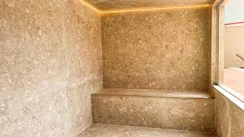 A bathroom with a marble floor, a bench, and a window.