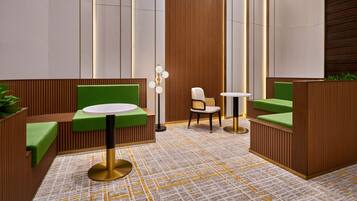 A modern lobby with green cushioned seating, a round table, and a patterned floor.