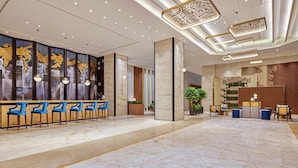 A modern hotel lobby with a reception desk, seating area, and decorative ceiling lights. - Hilton Garden Inn Wuhan Hankou (Wuhan)