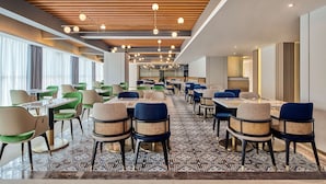 A modern dining area with multiple tables and chairs, wooden ceiling panels, and pendant lighting. - Hilton Garden Inn Wuhan Hankou (Wuhan)