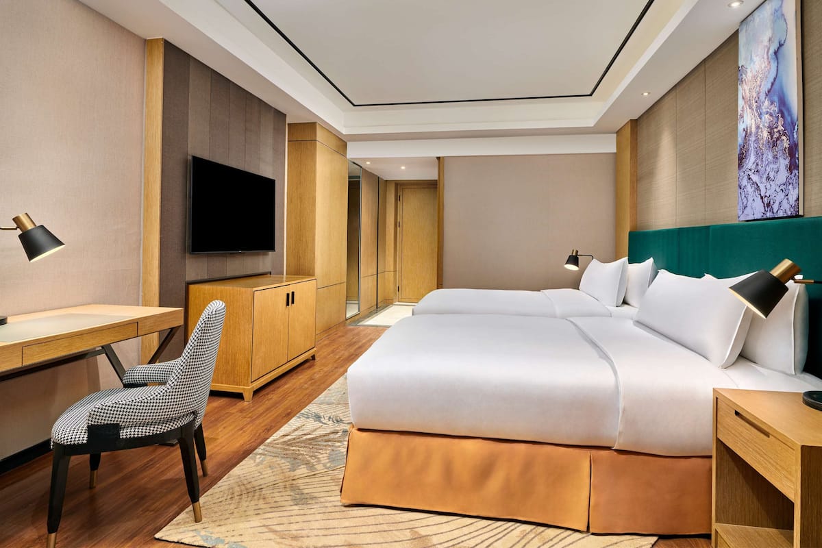 Ett modernt hotellrum med en stor säng, ett skrivbord, en stol, en TV och en garderob.