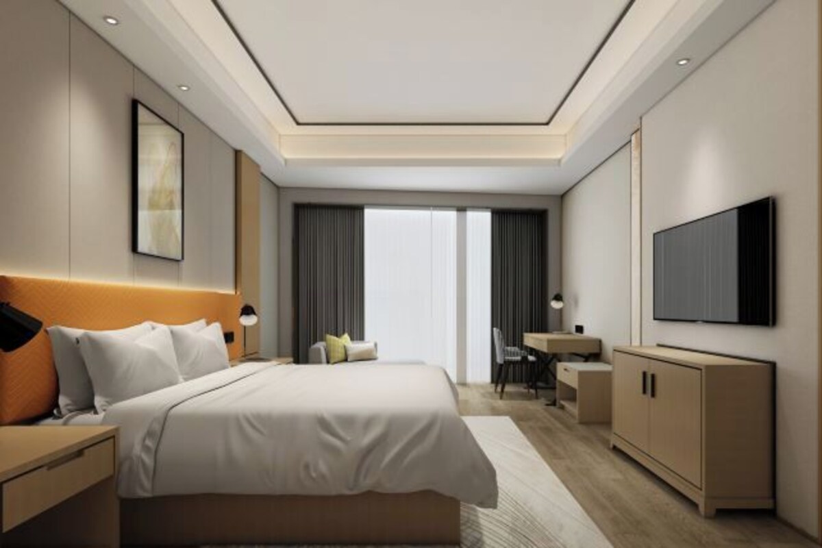 Une chambre d’hôtel moderne dotée d’un grand lit, d’un bureau, d’une télévision et offrant une vue sur la ville.