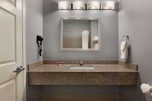 A bathroom with a granite countertop sink, a mirror above it, and a towel rack on the wall. - Days Inn by Wyndham Odessa (Odessa)