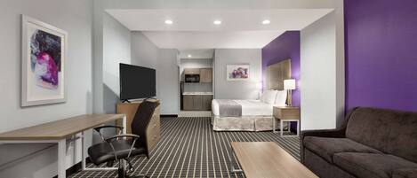 Ein modernes Hotelzimmer mit Bett, Schreibtisch, Stuhl, einer Sitzecke und einem Fernseher.
