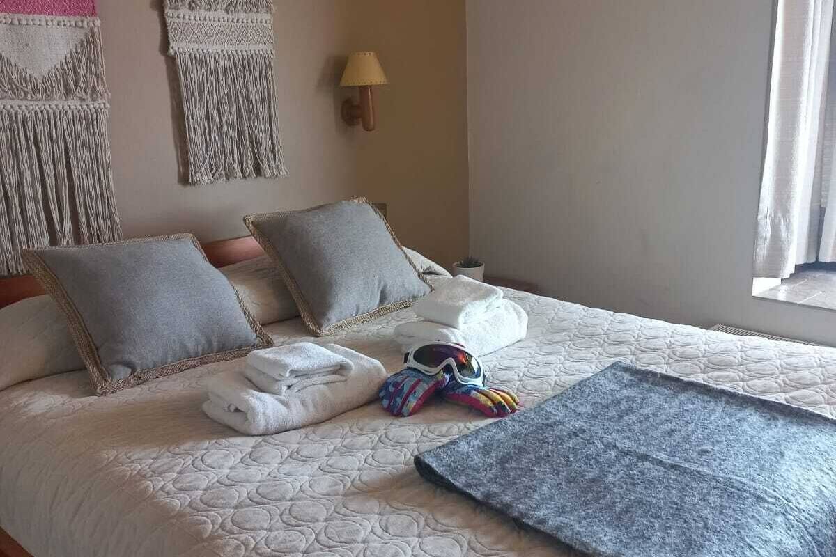 A neatly made bed with a quilted cover, two pillows, and a blanket. There are two wall hangings above the bed.