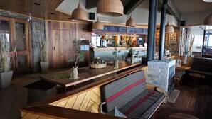 A cozy restaurant interior with wooden walls, a bar area, and hanging pendant lights. - Colorado Apart Hotel (Lo Barnechea)